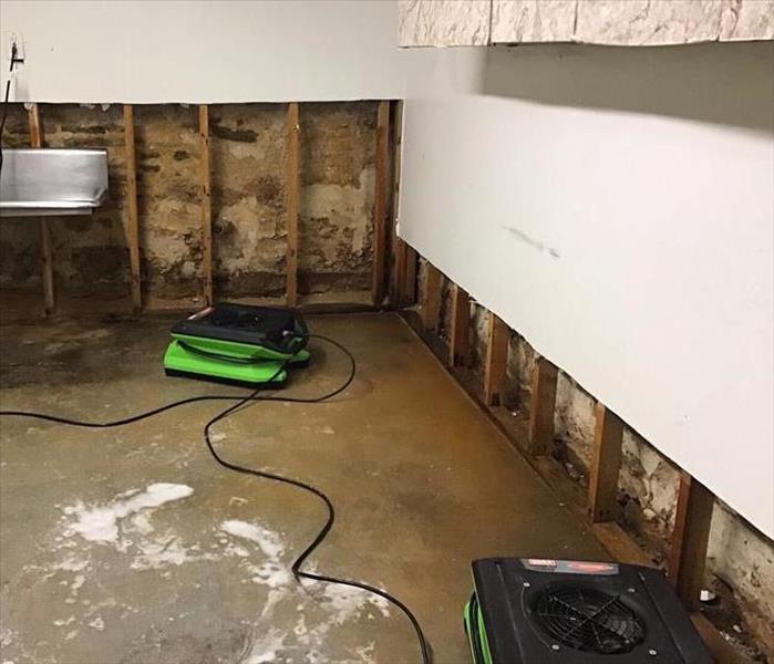 Wet flooring, flood cuts, and drying equipment in a basement.